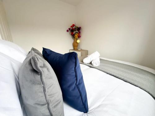 a bed with a blue pillow and a vase of flowers at Geranium House by Blue Skies Stays in Stockton-on-Tees