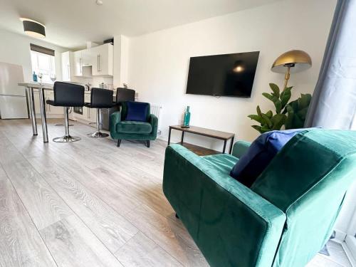 a living room with green chairs and a flat screen tv at Chestnut House by Blue Skies Stays in Middlesbrough