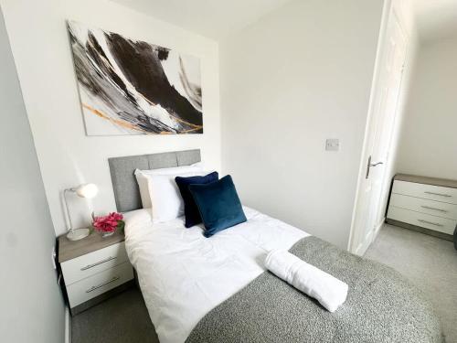 a bedroom with a bed with white and blue pillows at Deepdale House by Blue Skies Stays in Stockton-on-Tees