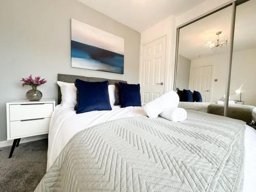 a bedroom with a large white bed with blue pillows at Turton House by Blue Skies Stays in Stockton-on-Tees