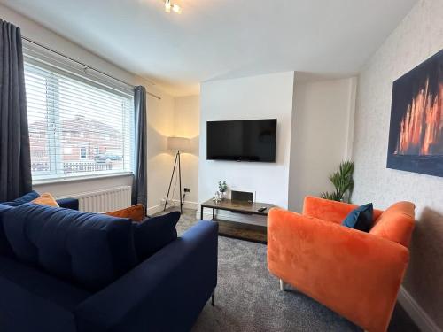 a living room with a blue couch and orange chairs at Turton House by Blue Skies Stays in Stockton-on-Tees