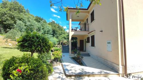 a large white house with a balcony and trees at Studio apartment Peršić in Mošćenice