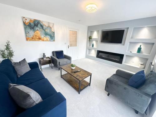 a living room with a blue couch and a tv at Fullerton House by Blue Skies Stays in Thornaby on Tees