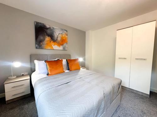 a bedroom with a bed with two orange pillows at Essex House by Blue Skies Stays in Stockton-on-Tees