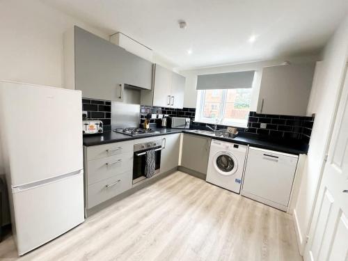 a kitchen with white cabinets and a washer and dryer at Essex House by Blue Skies Stays in Stockton-on-Tees