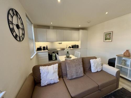 a living room with a couch and a clock on the wall at Gogmore Lane in Chertsey