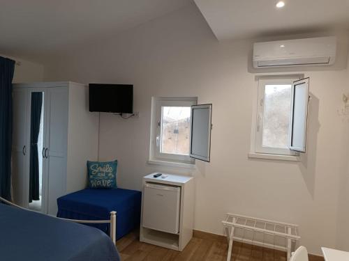 a living room with a blue chair and a tv at Oltremare in Cefalù