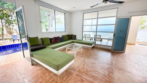 a living room with a green couch and a view of the ocean at Cabaña Costa de Oro in San Antero