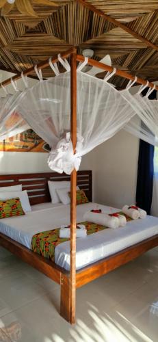 a bed with a canopy in a room at Long Beach Resort, Nosy Be in Nosy Be