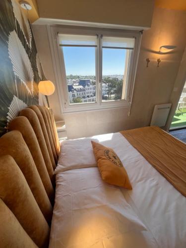 a bedroom with a large white bed with a window at Le Cézembre, au pied de la plage in Saint Malo