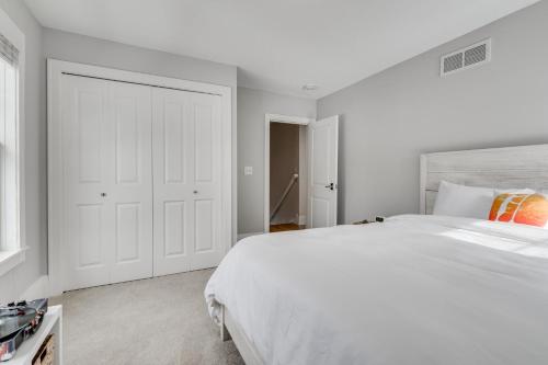 a white bedroom with a large white bed with an orange pillow at Lakefront Cottage in Excelsior