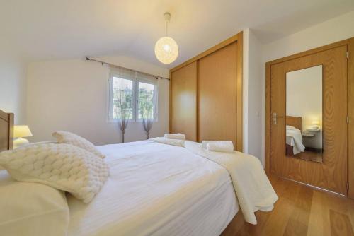 a bedroom with a large white bed and a bathroom at Vivenda Carlota Sea View by Mth in Ribeira Brava