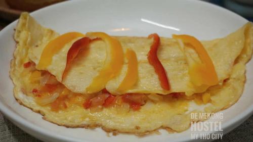 Una tortilla con pimientos naranjas en un plato blanco en DE MEKONG HOSTEL MY THO City, en Mỹ Tho