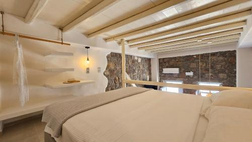 a bedroom with a bed and a stone wall at Efi's Apartments in Plaka Milou