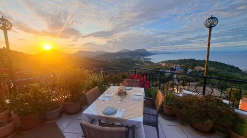 a table and chairs on a balcony with the sunset at 75 Steps Apartments in Mesongi