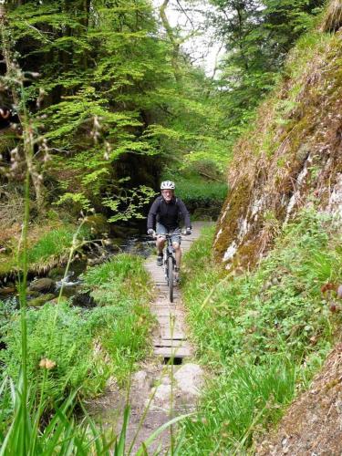a man riding a bike down a trail at ZEcamping 3 étoiles animaux acceptés piscine chauffée restaurant et soirées in Huelgoat