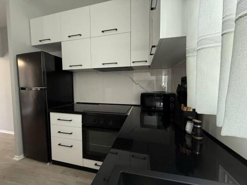 Una cocina con gabinetes blancos y electrodomésticos negros. en Izzy Apartment, en Vlorë