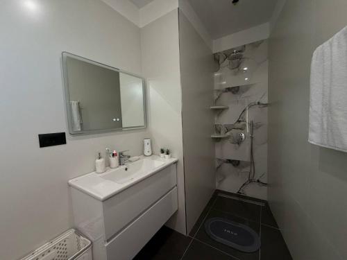 un baño blanco con lavabo y espejo en Izzy Apartment, en Vlorë