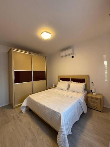 Un dormitorio con una gran cama blanca y una mesita de noche. en Izzy Apartment, en Vlorë