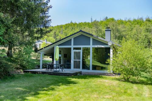 a cottage with a porch with a table on a lawn at 4 Personen mit Sauna F1H5 in Ruhla