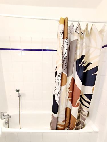 une baignoire avec un rideau de douche dans une salle de bain dans l'établissement Levalet BNB - La Défense, à Courbevoie