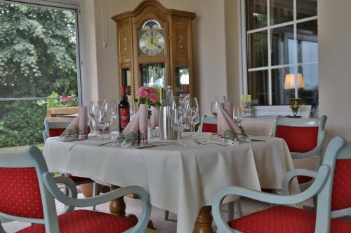 a table with wine glasses and a grandfather clock at Im Wiesengrund in Lalendorf