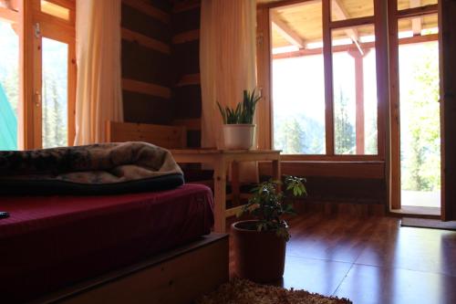 a room with a couch and a table with windows at Mysterious Kutla Cottage,Kutla, Tosh in Chhorang