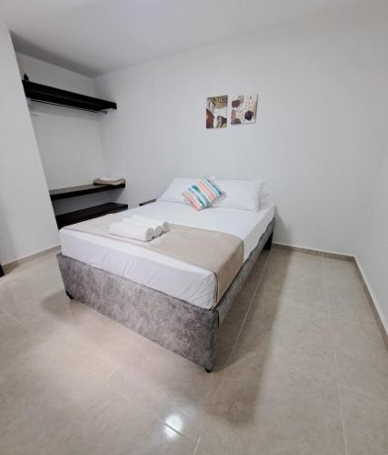 a white bed in a room with a white wall at Casa del Sol in Mariquita