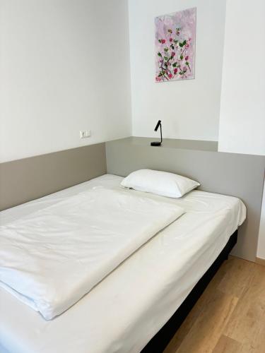 ein Bett mit weißen Laken und einer Lampe darauf in der Unterkunft Hotel Wasserpalast - breakfast for free!!! in Graz