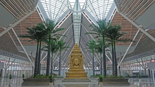 a large gold statue in a building with palm trees at Hello Cambodia Hotel in Phumi Ta Phul
