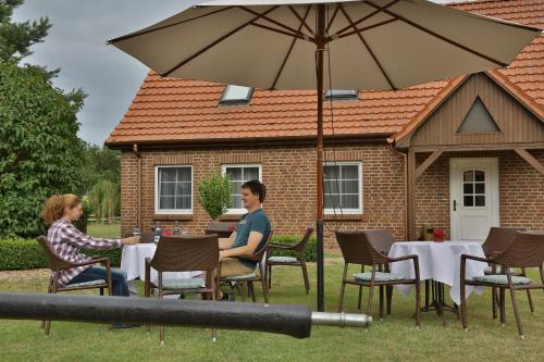 a man and woman sitting at a table under an umbrella at Im Wiesengrund in Lalendorf