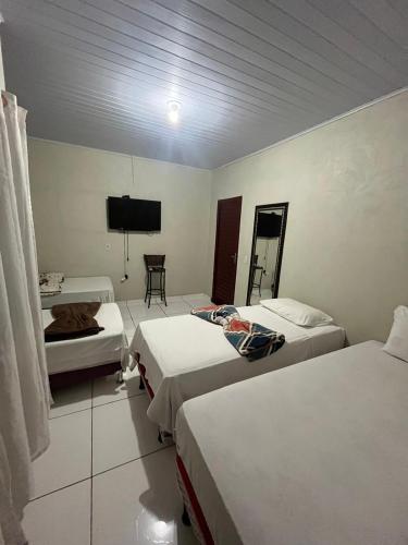 a hotel room with two beds and a flat screen tv at Pousada Mãe e Filhas in Mateiros