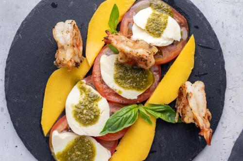 a plate of food with shrimp and tomatoes and bananas at Pumilio Mountain & Ocean Hotel in Jacó