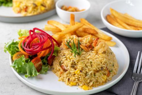 a plate of food with rice and french fries at Pumilio Mountain & Ocean Hotel in Jacó