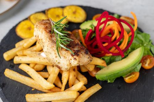 a plate of food with meat and french fries and vegetables at Pumilio Mountain & Ocean Hotel in Jacó