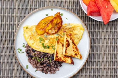 a plate of food with eggs and rice and fruit at Pumilio Mountain & Ocean Hotel in Jacó