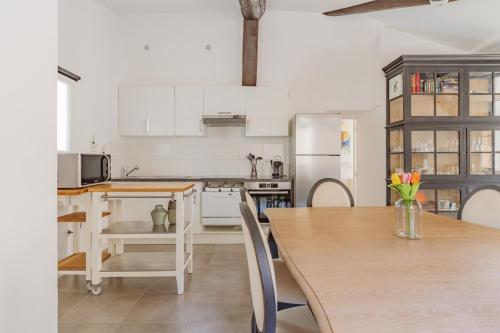 une cuisine avec des armoires blanches et une table en bois dans l'établissement Aix Historique La Tour de l 'Horloge, à Aix-en-Provence