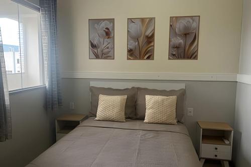 une chambre avec un lit avec trois tableaux au mur dans l'établissement 403 Apto Versátil e Aconchegante, à Belém