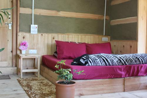 a bed in a wooden room with pink sheets at Mysterious Kutla Cottage,Kutla, Tosh in Chhorang