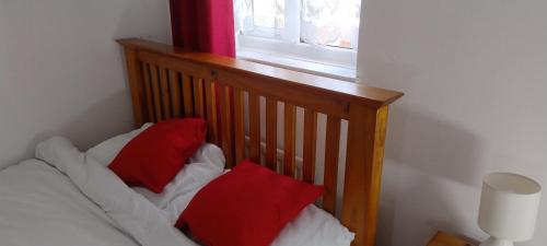 a bed with two red pillows on it next to a window at Entire 2 bedroom home with parking in Coventry, UK in Coventry