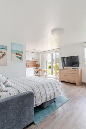 une chambre avec un grand lit et une télévision dans l'établissement Sardine argentée Plage à 100m Surf Randos GR 223 Jardin, à Surtainville