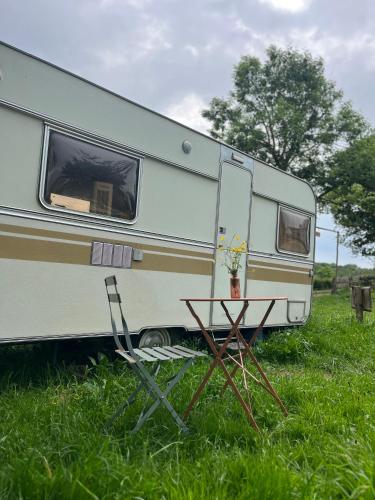 une caravane blanche garée dans un champ d'herbe dans l'établissement Séjour Bien Être nature, à Perrecy-les-Forges