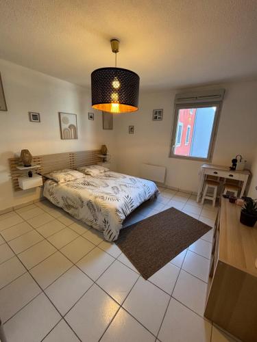 a bedroom with a bed and a table and a window at La Belle Garde in Toulouse