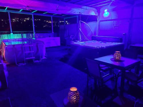 a dark room with purple lights and tables and chairs at בראשית שמיים in Yavneʼel