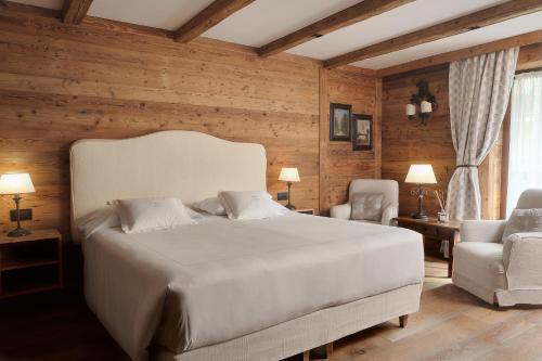 a bedroom with a large white bed and a chair at Auberge de La Maison in Courmayeur