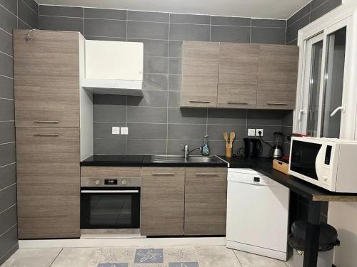 a kitchen with a sink and a microwave at Charmante maison à Lagord avec jardin privatif in Lagord
