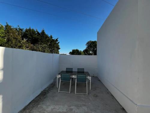 a patio with three chairs and a table against a white wall at Charmante maison à Lagord avec jardin privatif in Lagord