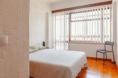 a bedroom with a bed and a chair and a window at Casa na Praia in Sesimbra