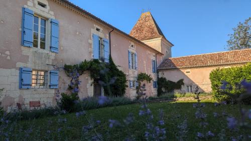 an old building with purple flowers in the yard at Maison Nathis in Saint-Sulpice-de-Roumagnac