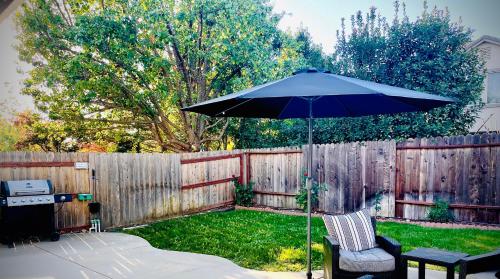 an umbrella and two chairs in a yard with a fence at Huge Home near Old Folsom Pet & Family Friendly in Folsom